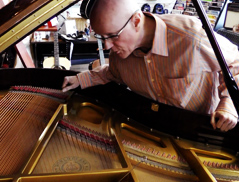 Pat Roak inspects the inside of a grand piano.
